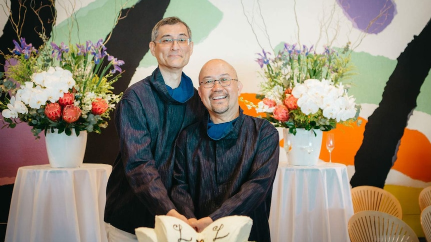 Two men in front of a wedding cake