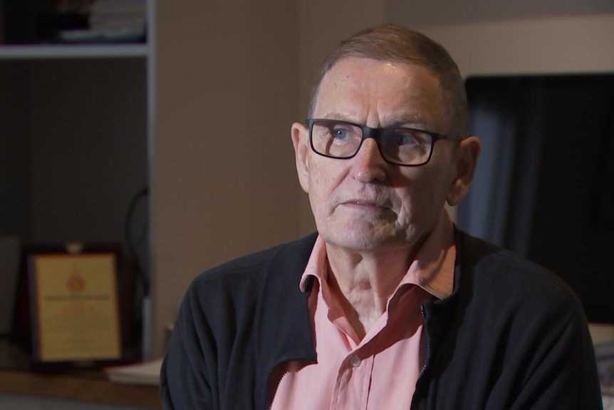 A man in glasses sitting in an office.