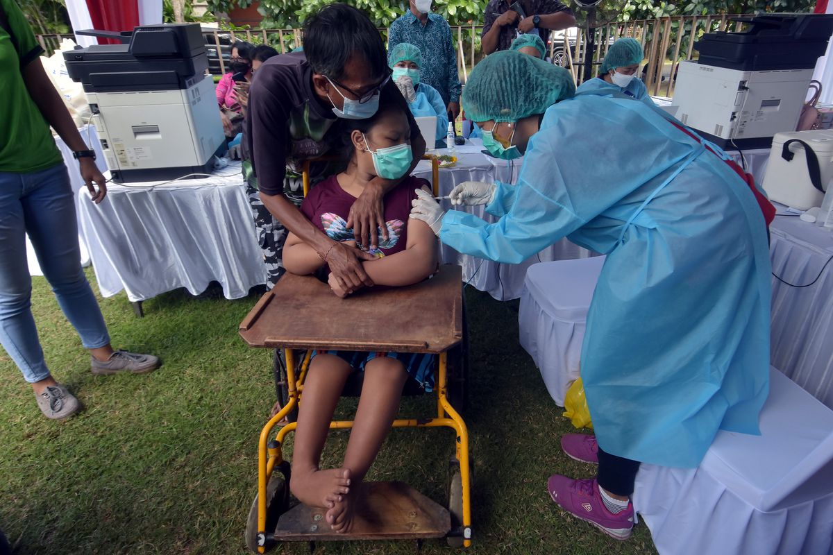 a woman sitting on a wheelchair getting a jab.