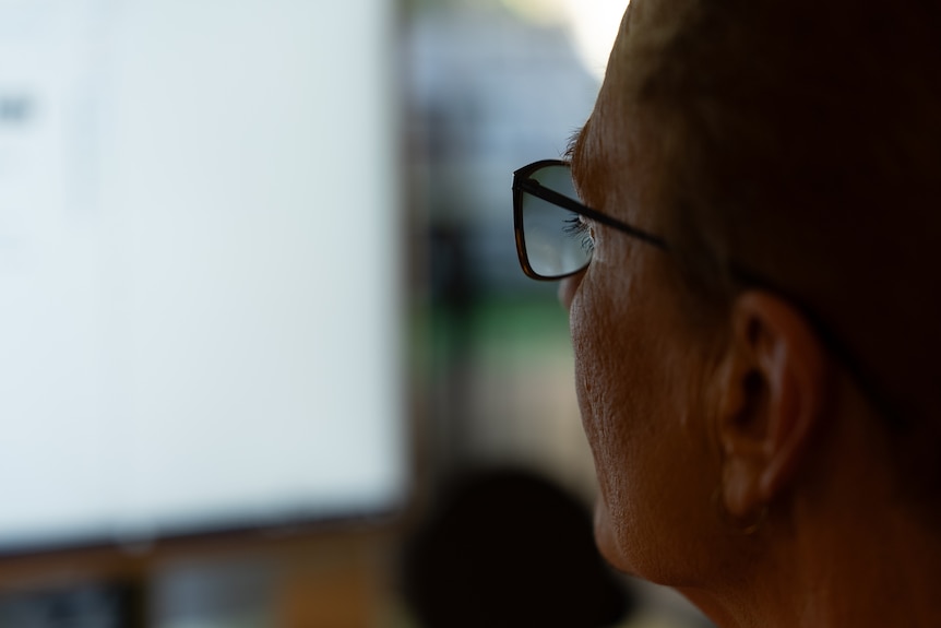 A woman looks at a computer screen.