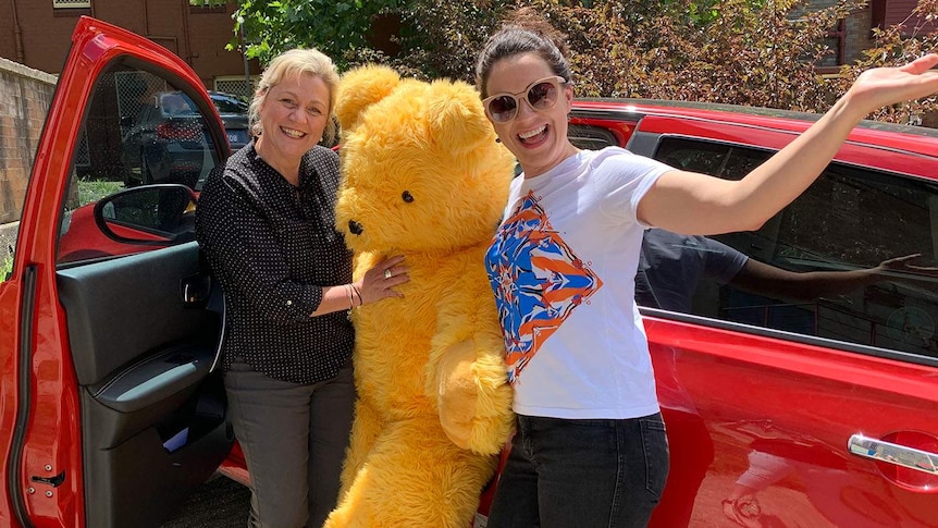 Laura, Meg and Big Ted standing next to a car