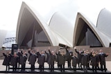 The 21 APEC leaders pose for their group photograph wearing tailor-made Driza-Bones at the Sydney Opera House.