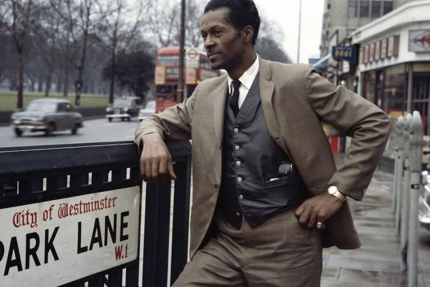 Chuck Berry leans on a London street sign