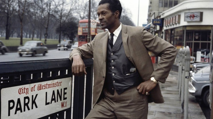 Chuck Berry leans on a London street sign