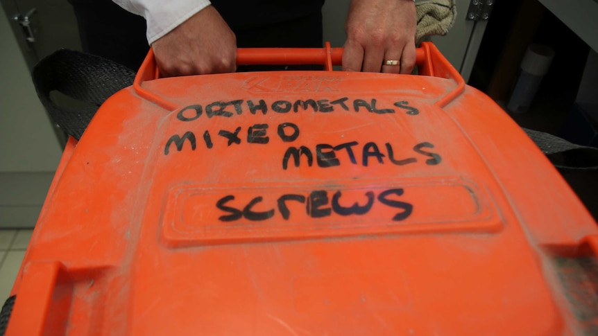 A large orange bin used to store metal screws to be recycled.