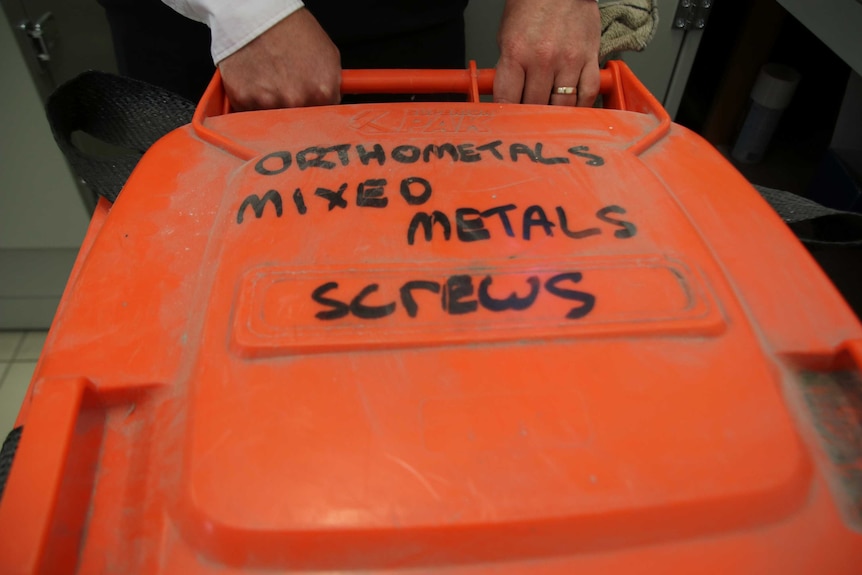 A large orange bin used to store metal screws to be recycled.