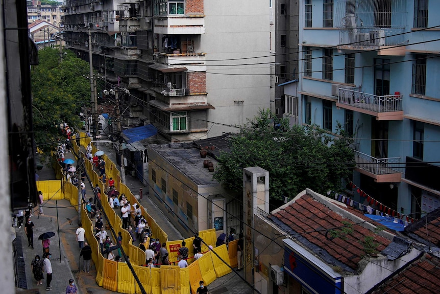 Residents wearing face masks line up for nucleic acid testings at a residential compound in Wuhan.