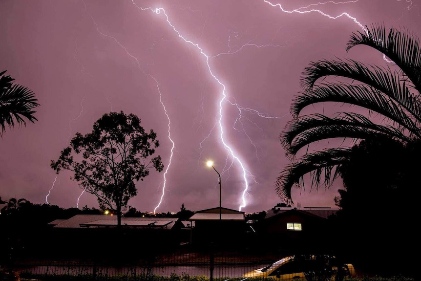 Lightning in the sky behind trees in Townsville at night