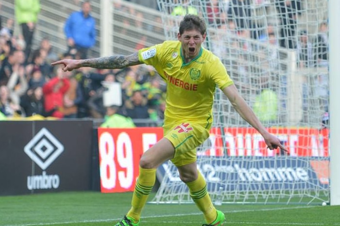 A man wearing yellow soccer jersey runs with his arms outstretched, yelling in apparent celebration.