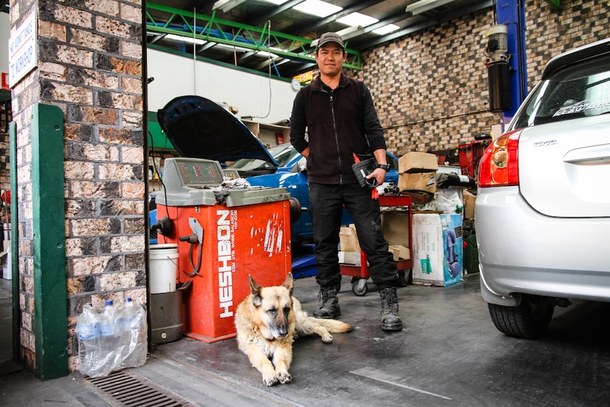 A man in his mechanics workshop with his dog