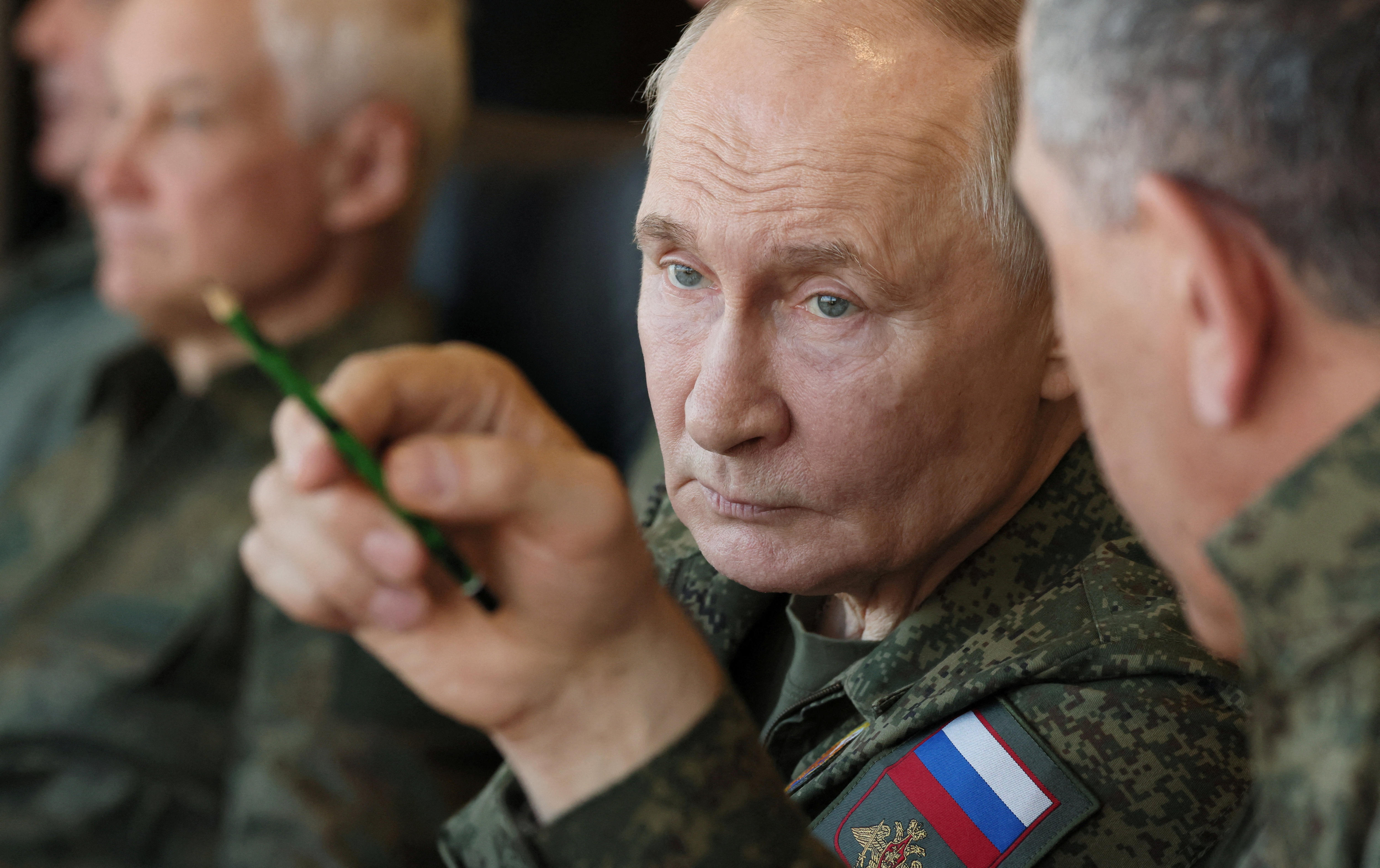 close up of vladimir putin as he receives advice from a russian military general