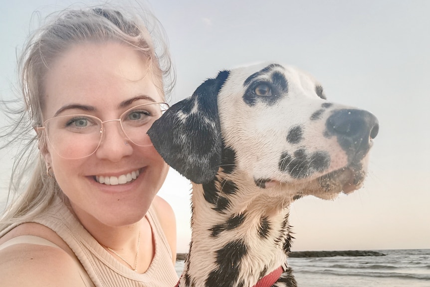 Casey Demko takes a selfie with her Dalmatian dog on the beach