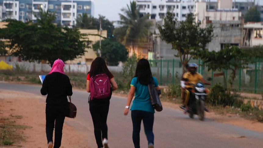 A motorist rides past young Indian girls in Bangalore.