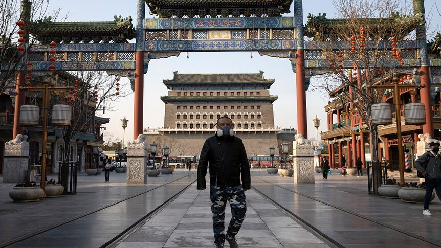 A man wearing a face mask walks through a quiet retail district in Beijing.