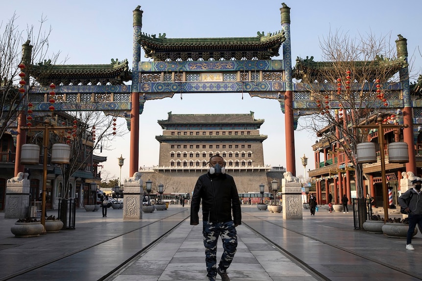 A man wearing a face mask walks through a quiet retail district in Beijing.