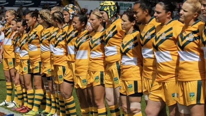 Australian Women's Rugby League team standing side by side in uniforms on the field in UK for the World Cup.
