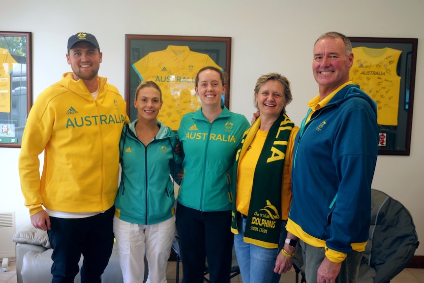 Five members of Emma McKeon's stand smiling at the camera, donned in Australian colours. 