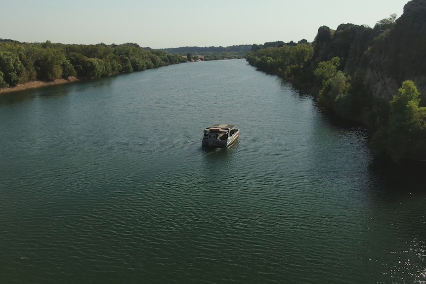 A boat on a calm river surrounded by trees