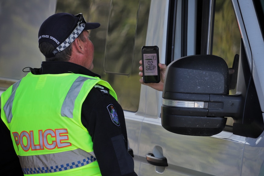 A police officer checks a motorist's border pass at a checkpoint on the Gold Coast Highway at Bilinga on August 26, 2020.