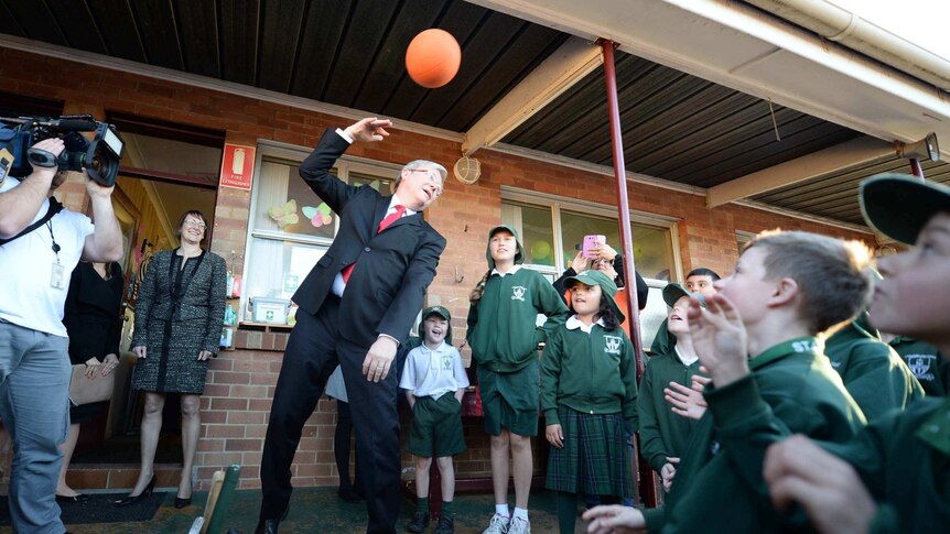 Kevin Rudd plays with a ball during a school visit