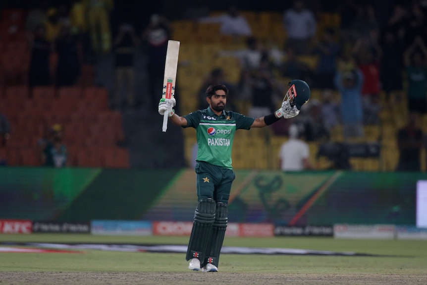 A Pakistan batsman raises his bat in one hand and his helmet in the other to salute the crowd after making 100 runs in an ODI.