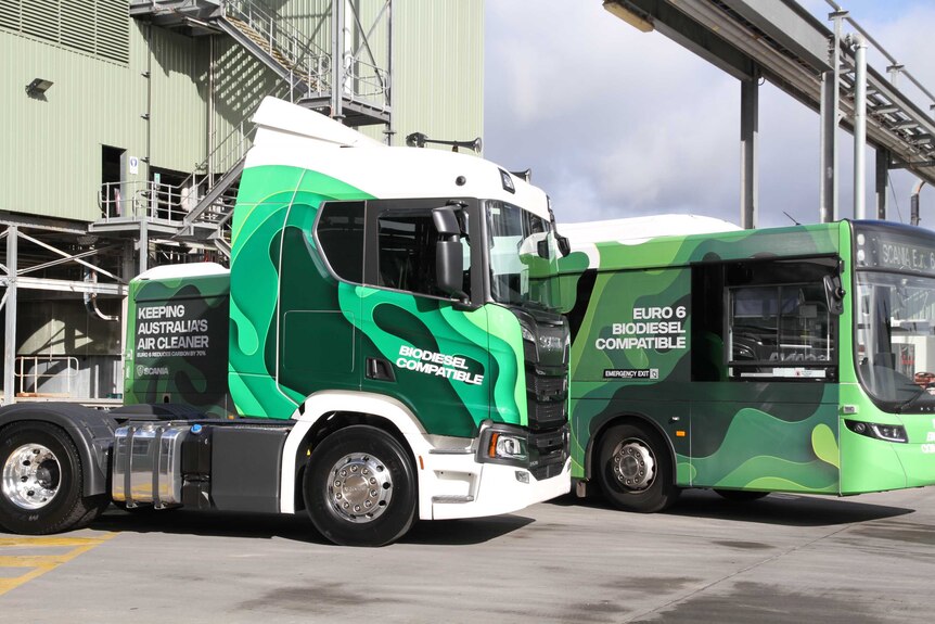 A truck and a bus are parked at a plant