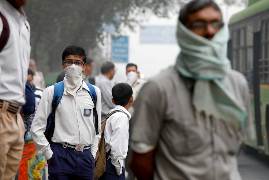 A schoolboy covers his face with a handkerchief.