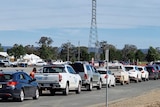 A long line of cars outside white tents.