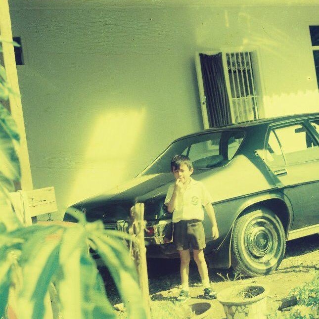 A green-tinged photo on a slant of a small child next to a Holden car.