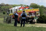 Police and emergency workers stand in a paddock near a gate