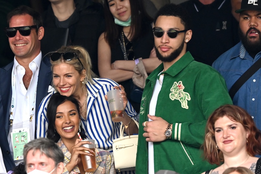 Ben Simmons stands as Sienna Miller hugs Maya Jama in the stands at Wimbledon.