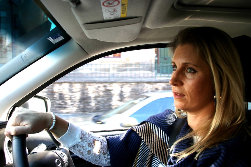A woman sits in the drivers seat of her car