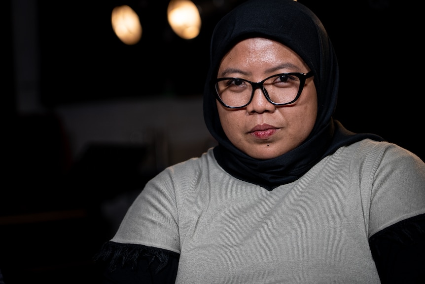 Seorang wanita Indonesia berhijab dan berkacamata melihat ke arah kamera