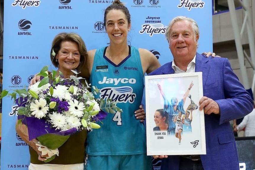 Jenna O'Hea is flanked by Gerry and Val Ryan, who are holding flowers and a print of Jenna