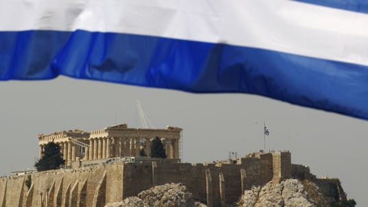 A Greek flag waves in front of the temple of the Parthenon in Athens