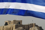 A Greek flag waves in front of the temple of the Parthenon in Athens