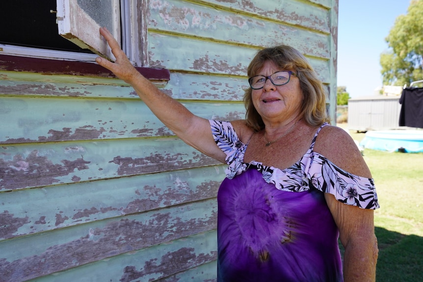 A woman pointing to the outside of her house