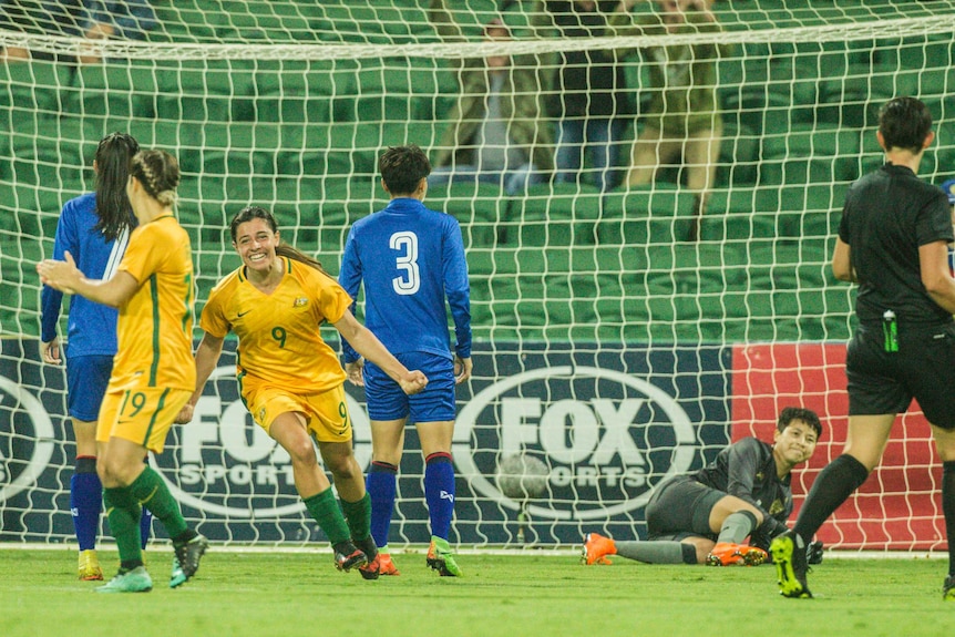 Alex Chidiac runs away smiling as other soccer players look on.