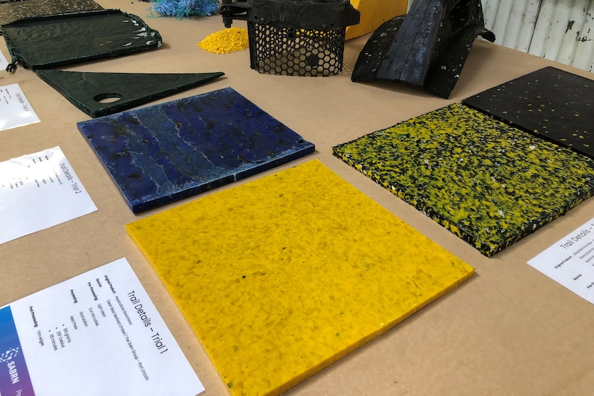 Multiple flat squares of plastic from yellow to blue sit on a table.