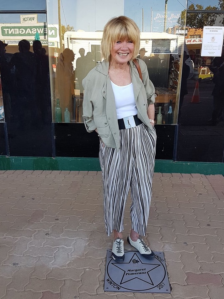 Woman in stripey pants stands on star in footpath