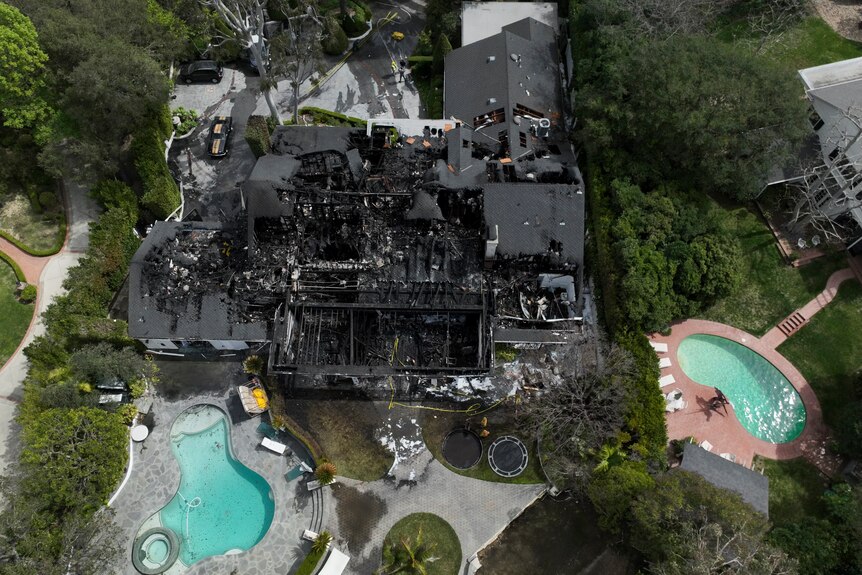 An aerial image of a burnt-down mansion with a swimming pool and greenery around