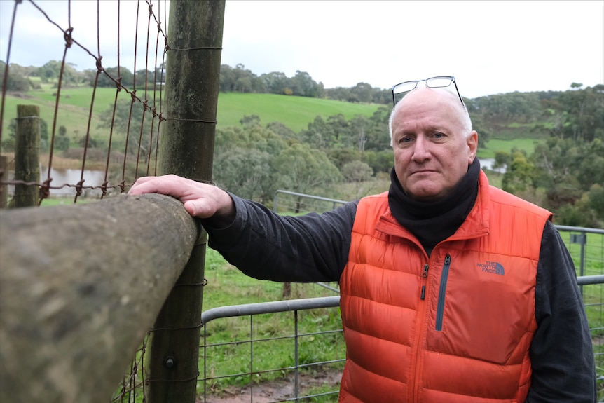 A man stands in front of rural land with two dams.