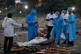 People wearing PPE stand around a deceased relative