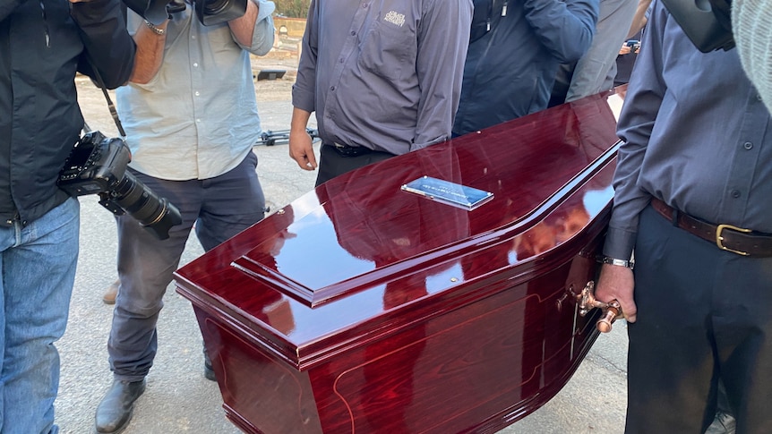 Cemetery authority staff carry a coffin for the Somerton Man's remains.