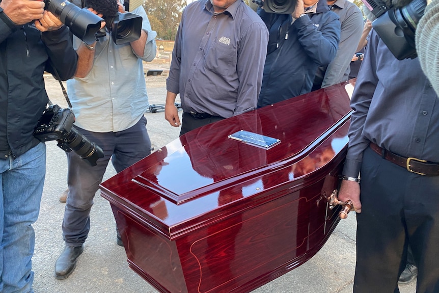 Cemetery authority staff carry a coffin for the Somerton Man's remains.