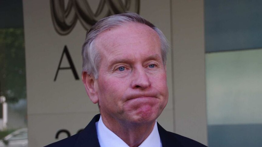 Colin Barnett, former WA Premier, looks glum, standing in front of an ABC sign.