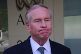 Colin Barnett, former WA Premier, looks glum, standing in front of an ABC sign.