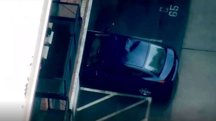 An aerial view of a blue sedan that has a large dent on the right of its roof