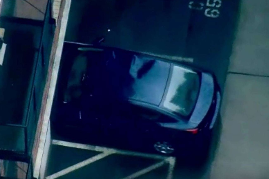 An aerial view of a blue sedan that has a large dent on the right of its roof