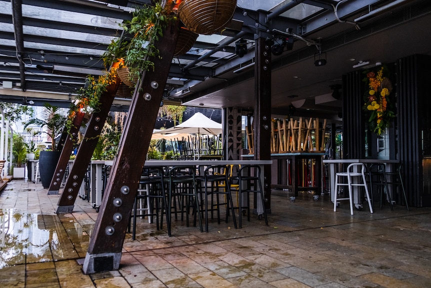 an empty outdoor area of a bar with empty tables and chairs